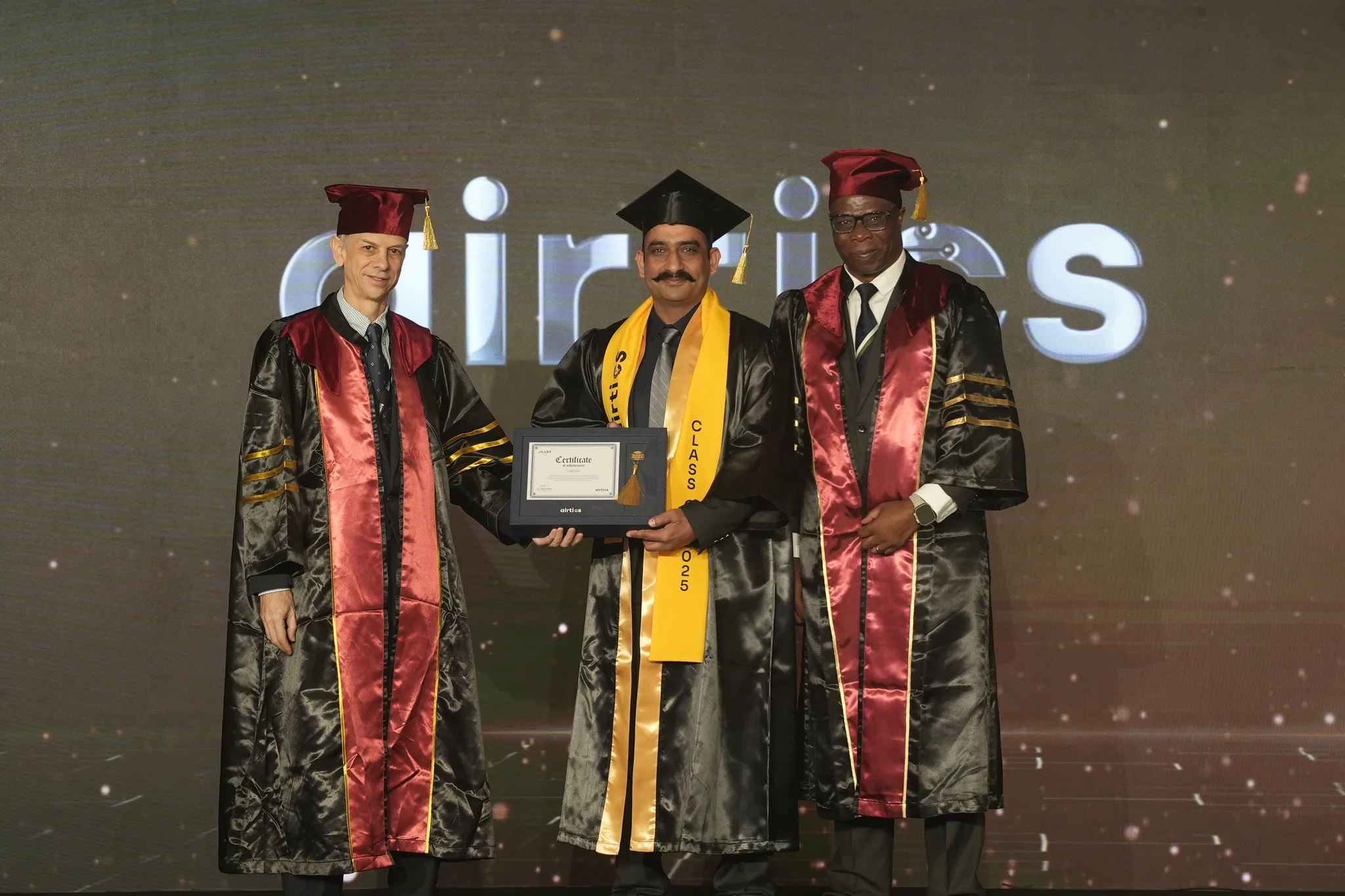 Airtics Graduation 2026: graduate receiving their certificate on stage from the Airtics academic panel